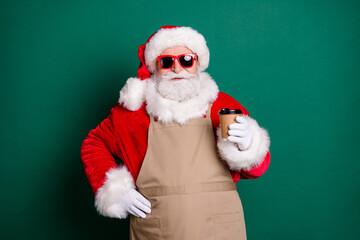 Portrait of his he nice handsome confident bearded cheery fat Santa waiter worker wearing apron drinking latte cappuccino selling beverage shop take away out service isolated green color background