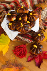 Homemade apple cakes in the shape of pumpkins, cosy colorful shawl or scarf and autumn leaves