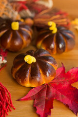 Homemade apple cakes in the shape of pumpkins, cosy colorful shawl or scarf and autumn leaves