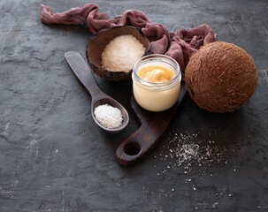 Whipped honey with coconut butter in a glass jar  and coconut shavings in a coconut shell on a dark background with space for text. Top view