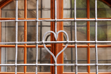 Forged metal grille with a heart in the middle in front of the window