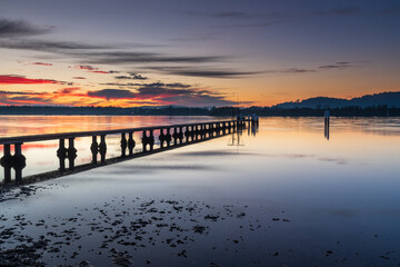 Fototapeta premium Clouds, reflections and sunrise over the bay