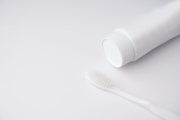 Blank tube of toothpaste and toothbrush on white background.