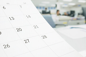 Close up white paper desk calendar on table with blurred office interior background