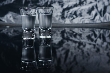 Vodka shots with ice on black table, copy space