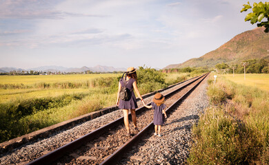 Mother with the daughter go on rails, back to a camera, on nature, in the summer
