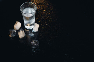 Vodka shot with ice on black table, copy space