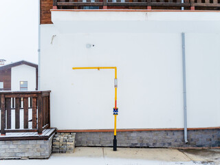 The yellow pipe adjoins the white wall of the house on the street