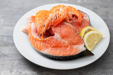 raw salmon with lemon on white dish on ceramic background