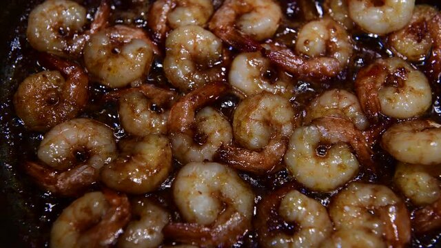 Shrimp fried in oil and soy sauce in a pan on the stove, cooking 4k video