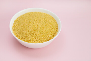 dry couscous in white bowl oin pink background
