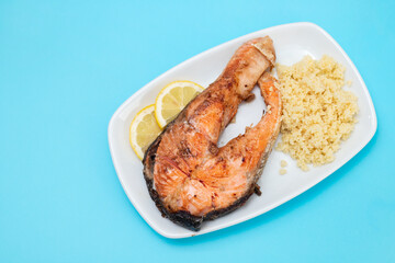 fried salmon with cous-cous on white dish on blue background