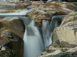 Long exposure stream of water falling between the rocks.