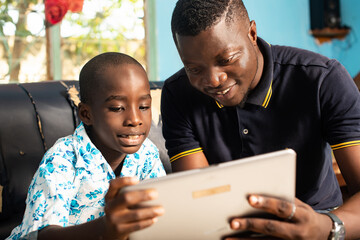 the father showing a digital tablet in his son's hand