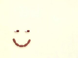 pills and capsules in the form of a smile on a beige background