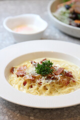 Pasta Carbonara. Spaghetti with bacon, parsel and parmesan cheese. Pasta Carbonara on white plate with parmesan on 
marble background. Italian food concept.