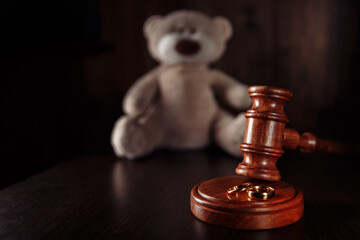 Divorce in family with children. Wooden gavel, rings and teddy bear.