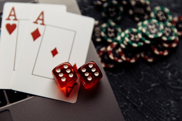 Chips, red dices and playing cards with aces for poker online or casino gambling on laptop keyboard close-up. Online casino concept.