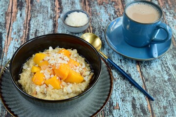Oat porridge breakfast with cubed mango and coconut chips. Served with hot chocolate