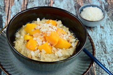 Oat porridge breakfast with cubed mango and coconut chips