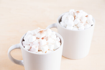 Two cups of hot cocoa with marshmallows on wooden background