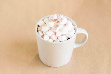 Cup of hot cocoa with marshmallows on brown background