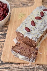 Homemade vegan gluten free kidney bean banana chocolate cake topped with coconut butter and hemp seeds on wooden board