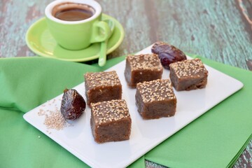 Dates tahini square sweet bites topped with sesame seeds. Served with espresso coffee.
