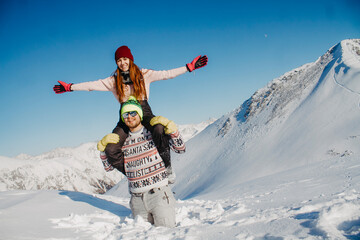 A loving couple in the winter in the mountains. Husband and wife rejoice in the snow.