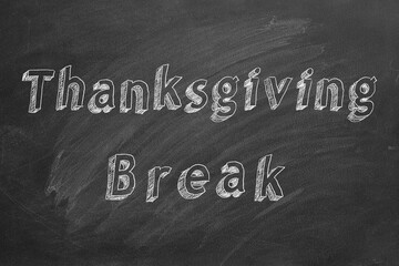 Hand drawing text "Thanksgiving Break" on blackboard