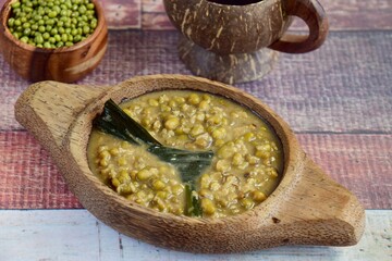 Bubur Kacang Hijau, Indonesian dessert made from mung beans cooked in coconut milk and palm sugar flavored with pandan leaves. Served on wooden bowl with tea