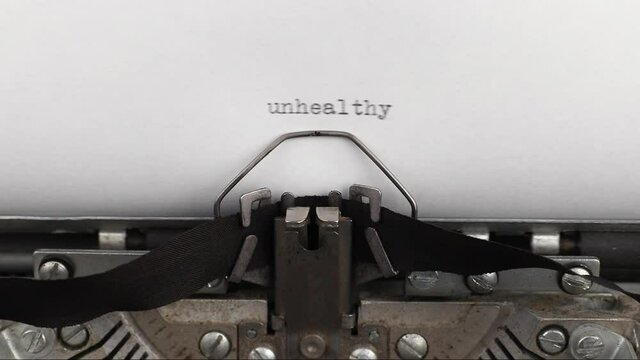 to type a quote unhealthy on a vintage and old typewriter close-up