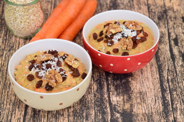 Carrot oat porridge with raisin, walnut and coconut flakes. Wooden background