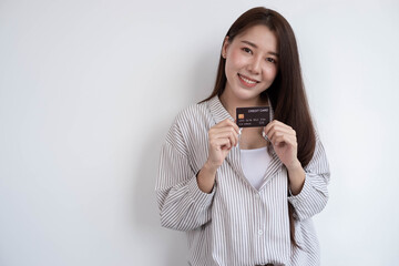 Portrait of a beautiful and cute Asian woman smiling and standing with a credit card on a white background, copy space.