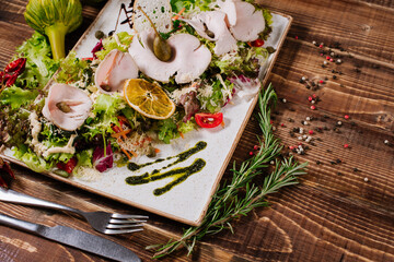 A dish with smoked ham and vegetables on wooden background