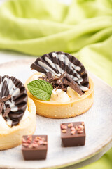 Sweet tartlets with chocolate and cheese cream with cup of coffee on a gray concrete background. side view, selective focus.