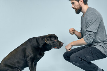 The man trains the dog indoors and gestures with his hands to execute the model's commands