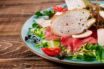 A dish with red fish, cheese and mushrooms on wooden background