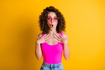 Photo of pretty shocked wavy hairdo lady summer black friday shopping low prices open mouth arms on chest unbelievable wear sun glasses tank top singlet isolated yellow color background