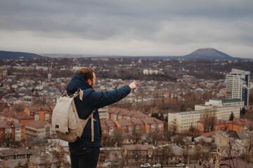 Male tourist on the observation deck overlooking the mountains. The traveler from the back points into the distance.