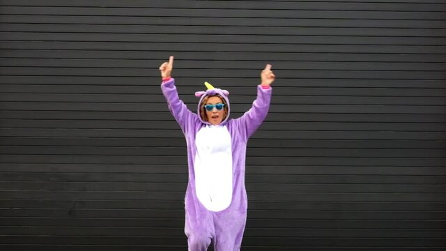 Crazy unicorn mask dance with funny people - cheerful happy adult woman dancing with carnival dress with black wall in background - Fun and happiness concept