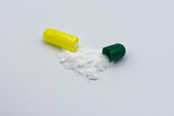 medication, open pill capsule on white background. Yellow and green