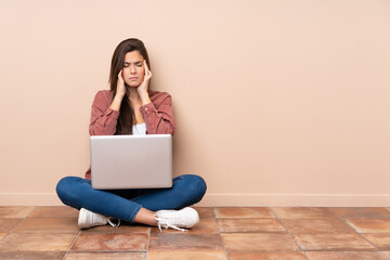 Fototapeta Teenager student girl sitting on the floor with a laptop with headache obraz