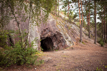 Landscape with cave and forest. Scenic entrance to cave. Rock wall with a dark hole. Spro, Mineral...