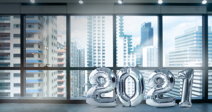 Metallic silver number balloons in modern office near big window and building view in city, 2021 Happy new year