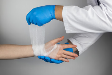The traumatologist applies a bandage to the patient's wrist. The concept of helping with fractures and sprains. The technique of applying a cruciform bandage.