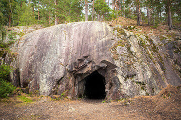 Landscape with cave and forest. Scenic entrance to cave. Rock wall with a dark hole. Spro, Mineral...