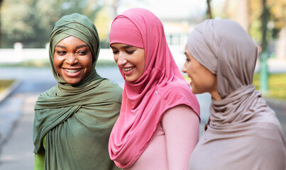 Three Cheerful Muslim Women In Hijab Walking And Talking Outdoors