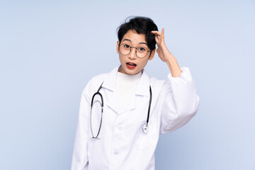 Fototapeta premium Doctor Asian woman over isolated blue background with surprise and shocked facial expression