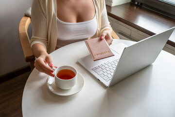 Woman with passport and laptop, cup of coffee sitting in cafe near window. making order and booking. Online service. concept.